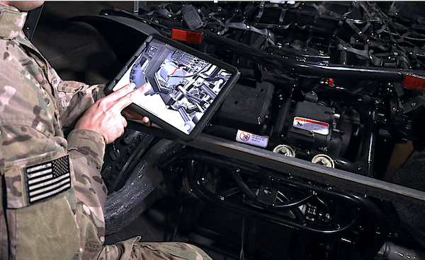 Depiction of military personnel using BILT 3D interactive instructions while on maintenance duty