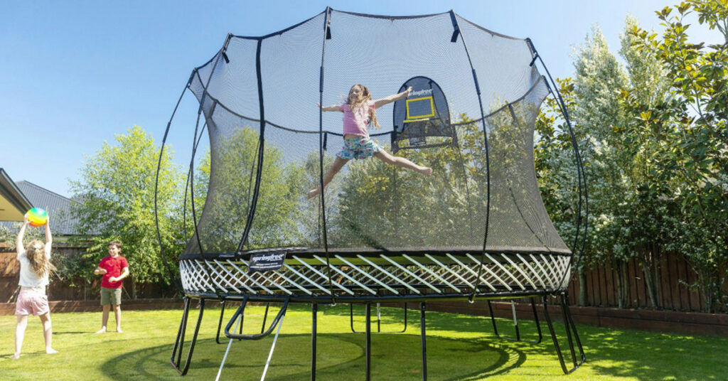 Girl jumping on Springfree Trampoline in a suburban back yard