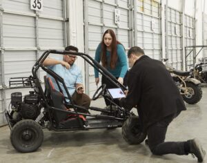 three young adults surround an offroad vehicle to perform an assembly analysis in the BILT warehouse