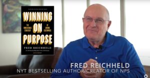 A black book titled Winning on Purpose floats to the left while author Fred Reichheld sits to the right. He is wearing a blue shirt and glasses.
