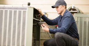 Field service hvac employee works on home unit while holding a tablet
